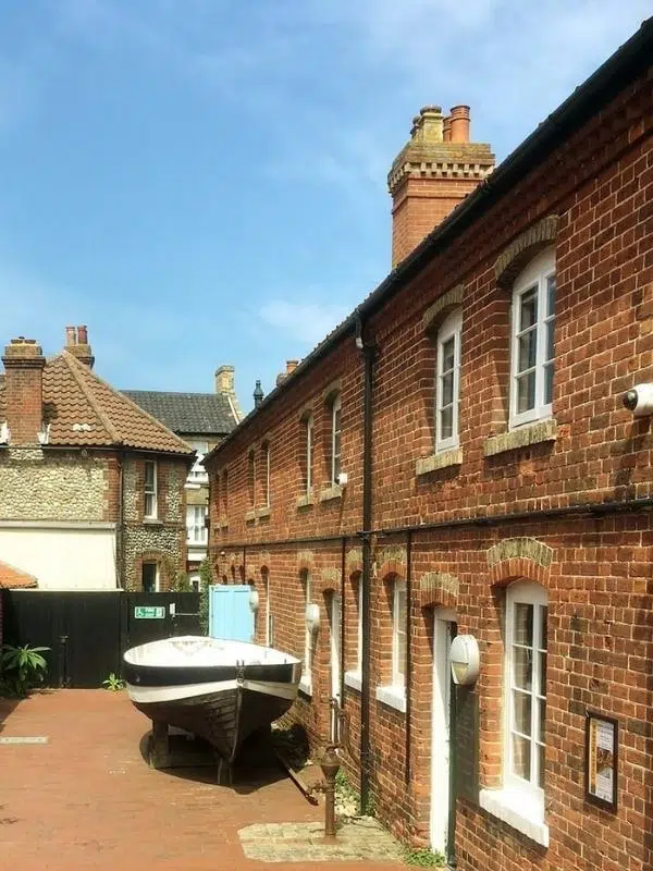 red brick terraced houses with a black and white boat in the yard and an old fashioned wtare pump by one of the doors