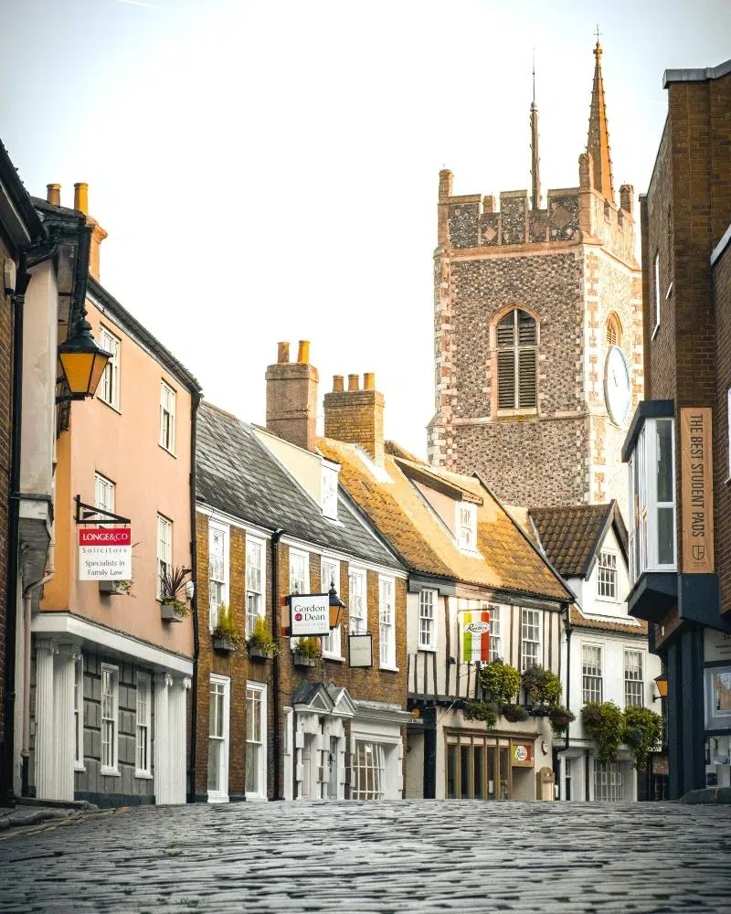 cobbled street with flint stone church tower in the background