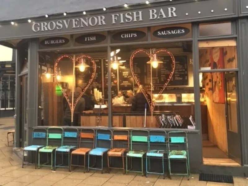 Grosvenor fish bar with colourful chairs lined up outside and pretty lighting inside