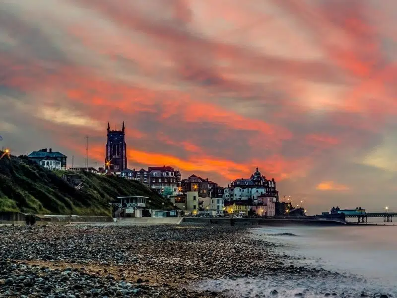 Cromer with the parish church dominating the skyline, Background of orange and grey sky.