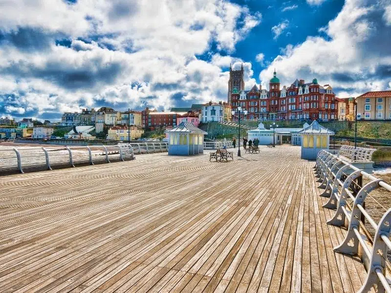 wooden pier with white metal railings and colourful buildings