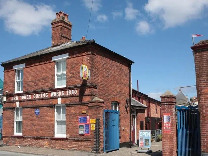 red brick house with blue gates to a courtyard and white writing on the front of the house