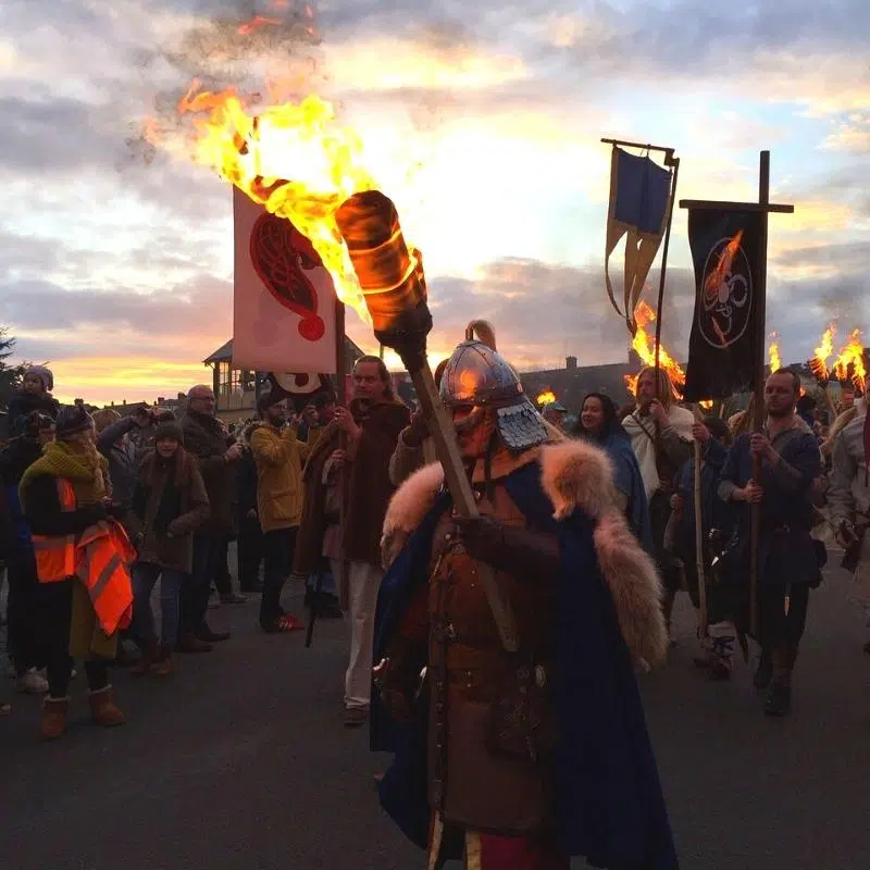 People dressed as Vikings carrying lot torches at twilight