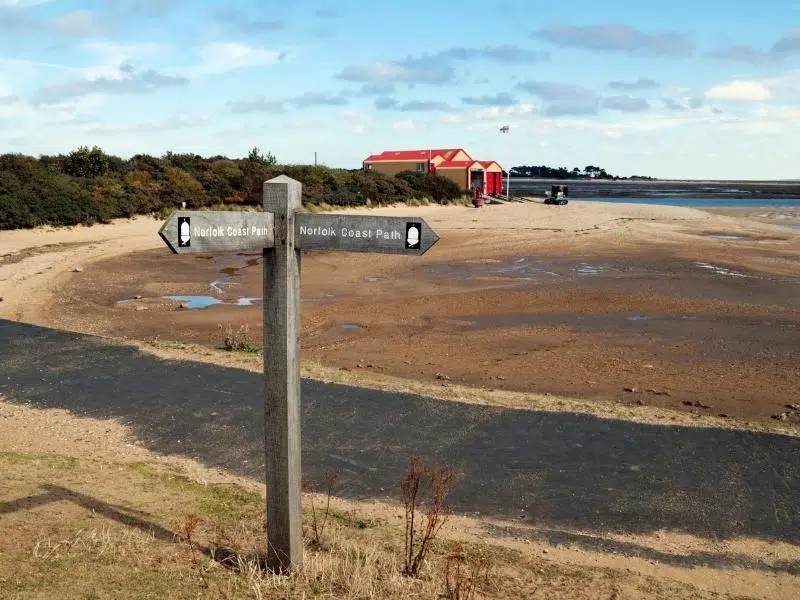 North Norfolk path sign on a sandy path with lifeboat sheds in the background