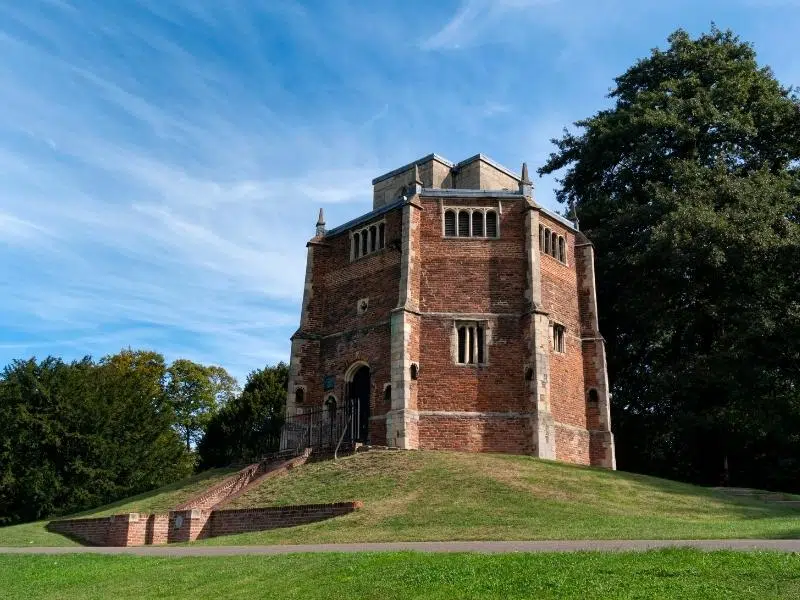 red brick historical octagonal building on a small grassy mound