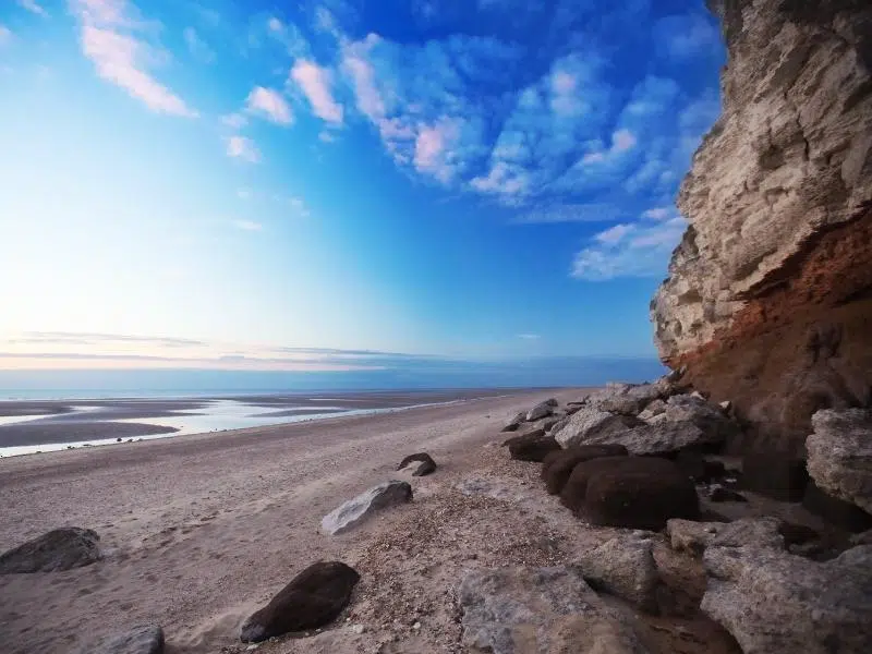 Vivid blue skies above single beach at low tode with cliffs behind