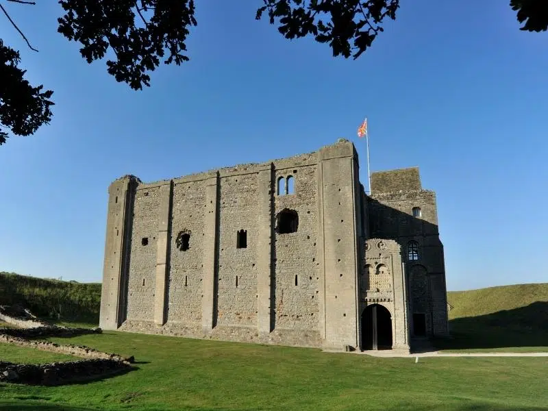 Medieval castle surrounded by grass with flag of St George flying from the top