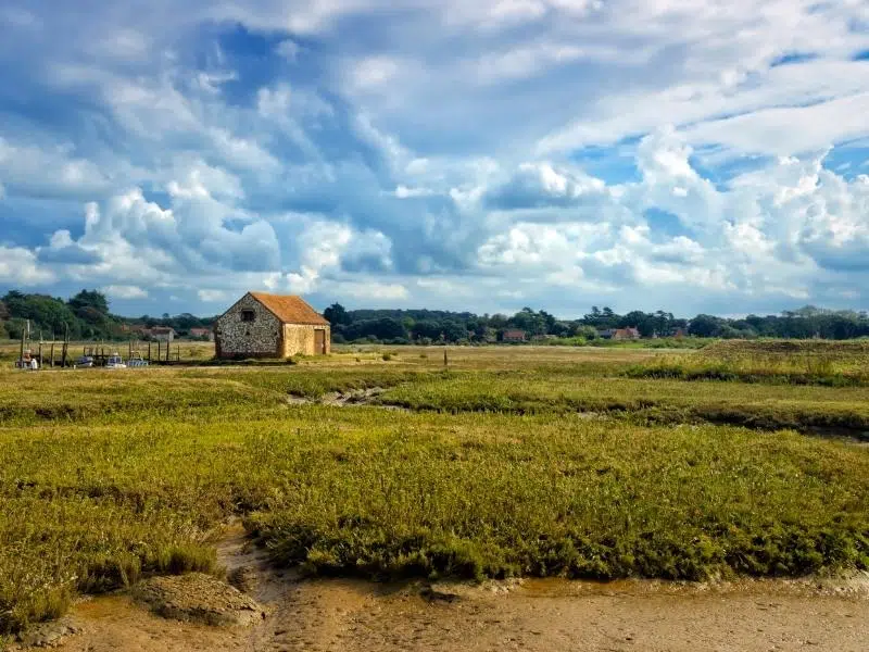 old brick and flint building set in salt marshes