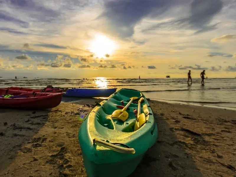 green, red and blue kayaks on a west facing beach
