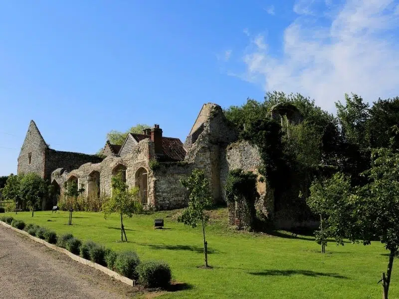ruins of an old stone and brick buildings surrouned by grass and trees