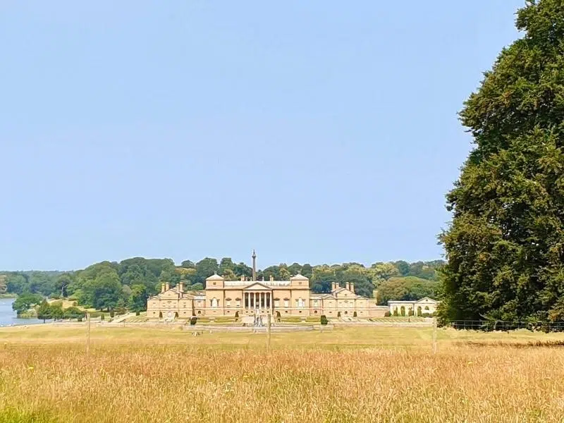 An image of Holkham hall, with an expanse of grass in the front and blue skies
