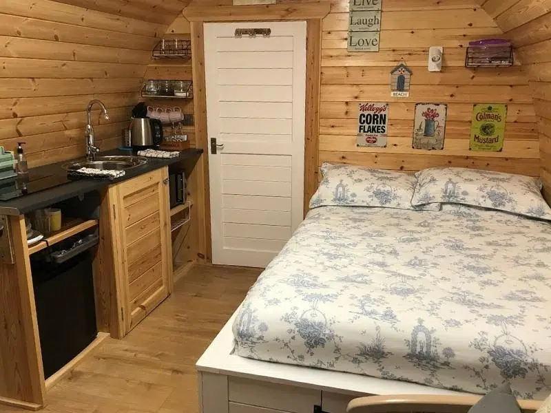 bed and small kitchen in wooden camping pod
