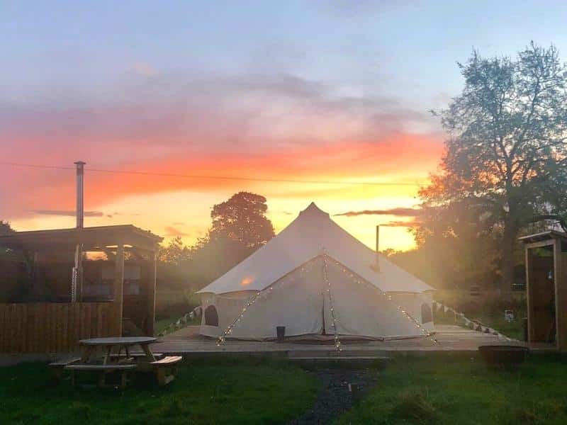 Bell tent with fairly lights at sunset