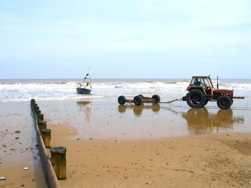 Crabbing boat coming into to Cromer beach, with a tractor ready to bring it onot shore