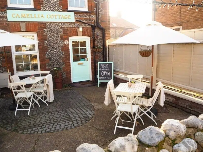 Pretty flint cottage courtyard with cafe seating, sun shades and signage