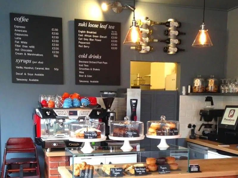 The counter of The Kitchen Sheringham, with menu boards, cakes and coffee machine