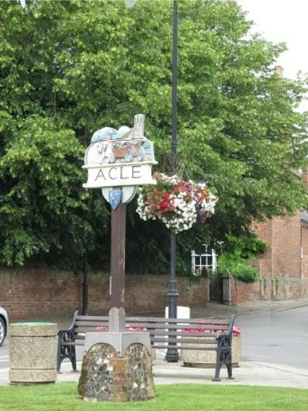 Toen sign in Acle with hanging baskets and a bench