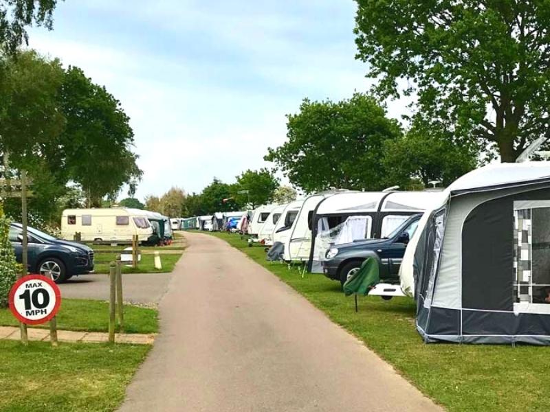 Row of caravans and motorhomes with awnings on grass pitches