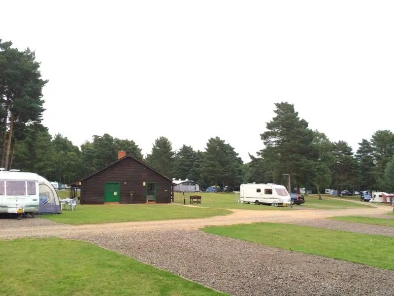 Caravans camping on grass near a wooden building