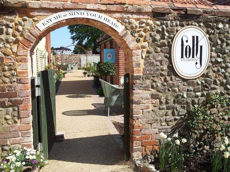 Folly Tearoom sign on flint wall beside a brick arch 