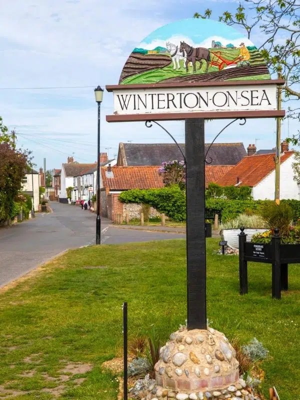 Winterton on Sea village sign with traditional houses in the background