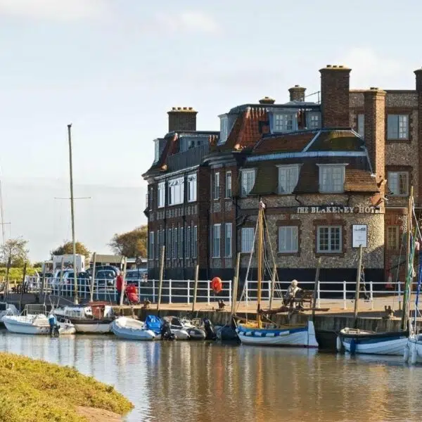 An image of the Blakeney Hotel kn the Quay with small sailboats in the forefront