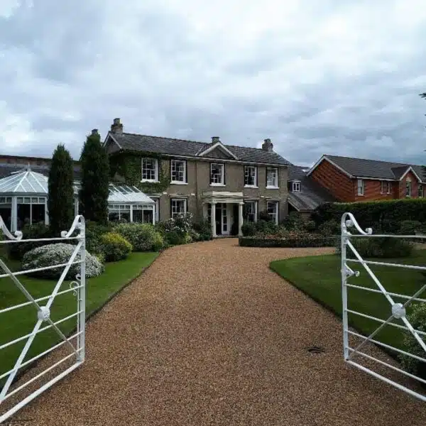 An image of a Georgian house set in beautiful gardens with a white iron gate