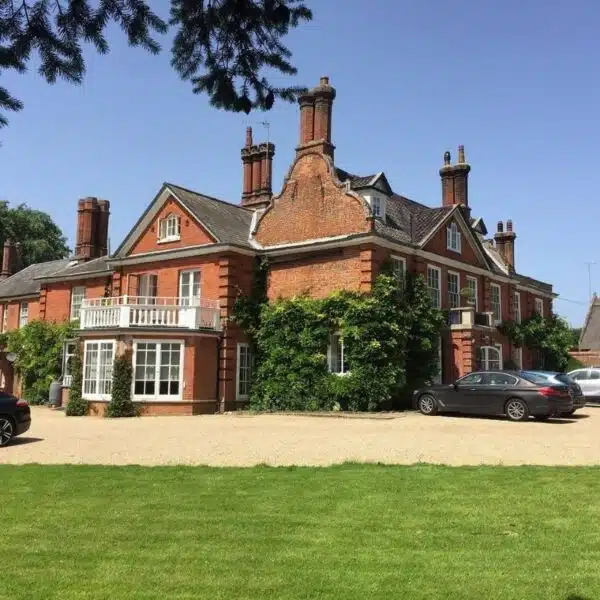 An image of a grand Georgian house with. a-gravel driveway and green lawn