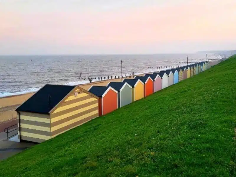 colourful beach huts with ashphalt roofs above a beach and the sea