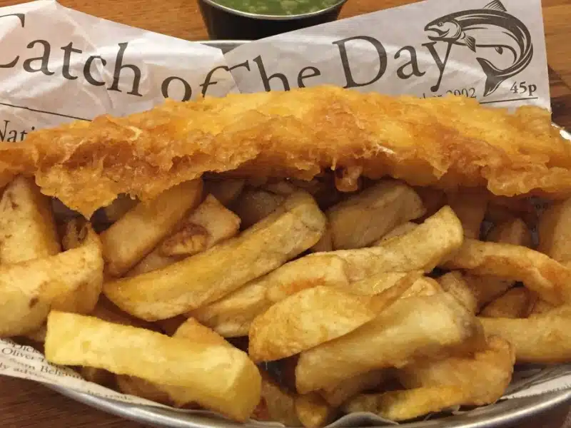 Fish and chips served in paper with 'catch of the day' written on it