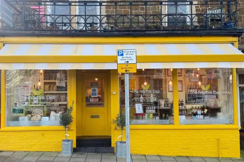 yellow painted double shop front with yellow and white striped awning