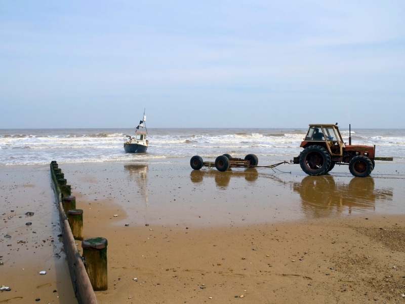Cromer fishing boat in the surf with a tractor on the beach