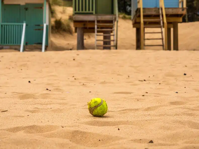 Tennis ball in the sands in front of beach huts