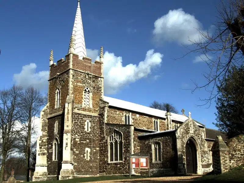 A brick and flint built church with a small tower and spire