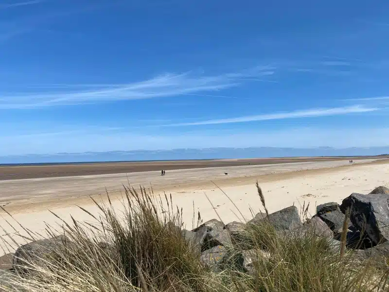 Brancaster Beach seen over rocks and Marram grass