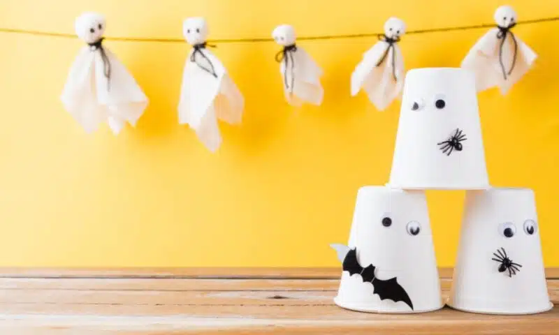 fabric ghost puppets tied to a line with paper vup ghosts decorated with plastic eyes, bats and spiders in the foreground
