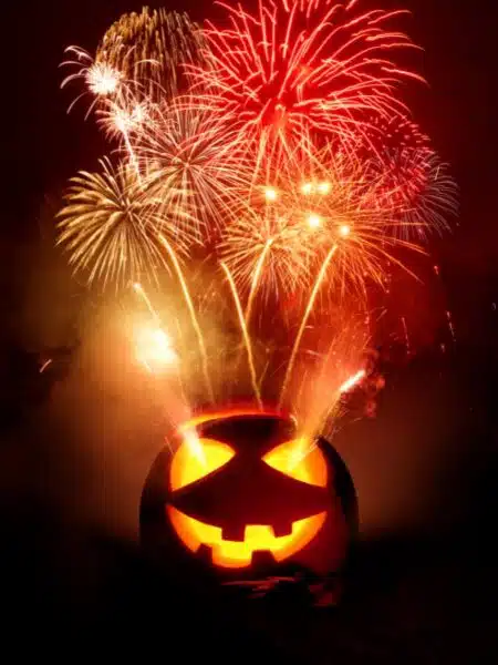 carved pumpkin with red and orange fireworks in the background