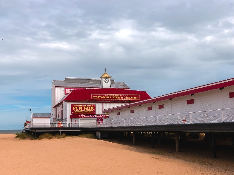 red and white pier with a small clock tower built over a fine sandy beach