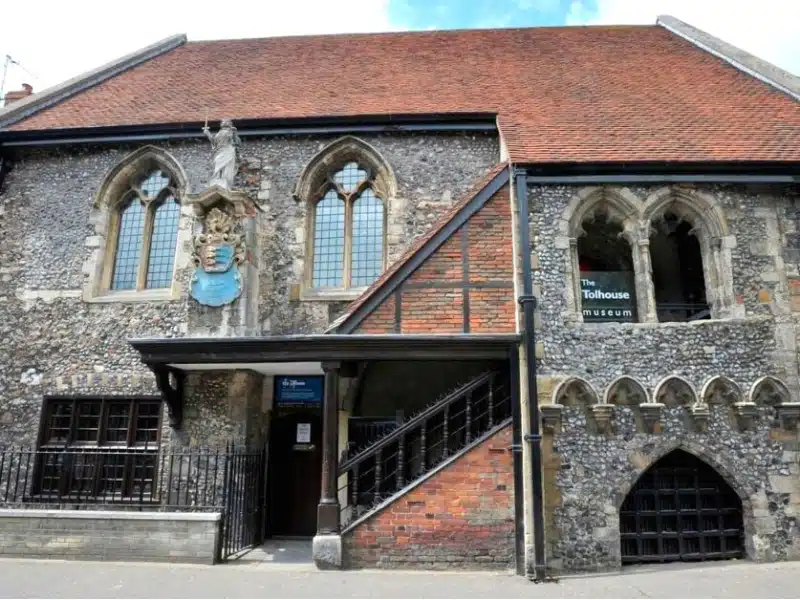 Flint building with red tiled roof and blue plaque