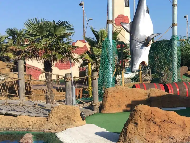 mini golf course with a plastic shark and tropical plants