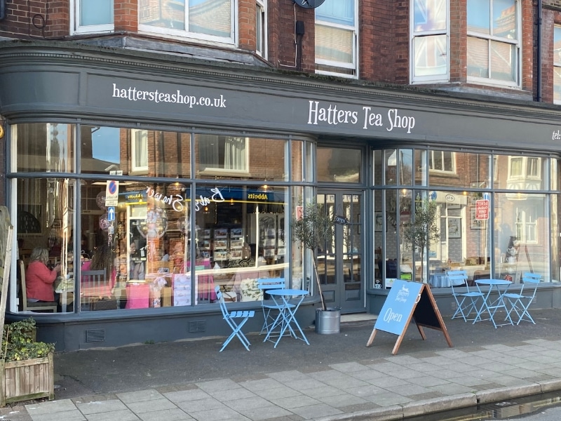 tea shop with grey painted frontage and blue chairs and tables outside on the pavement